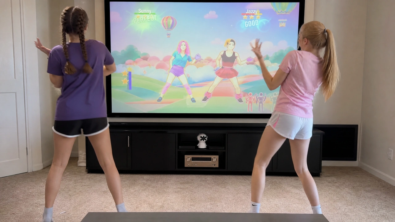 Two girls dancing in front of a big screen playing a motion-controlled dance game scored in real time by the Plaik camera